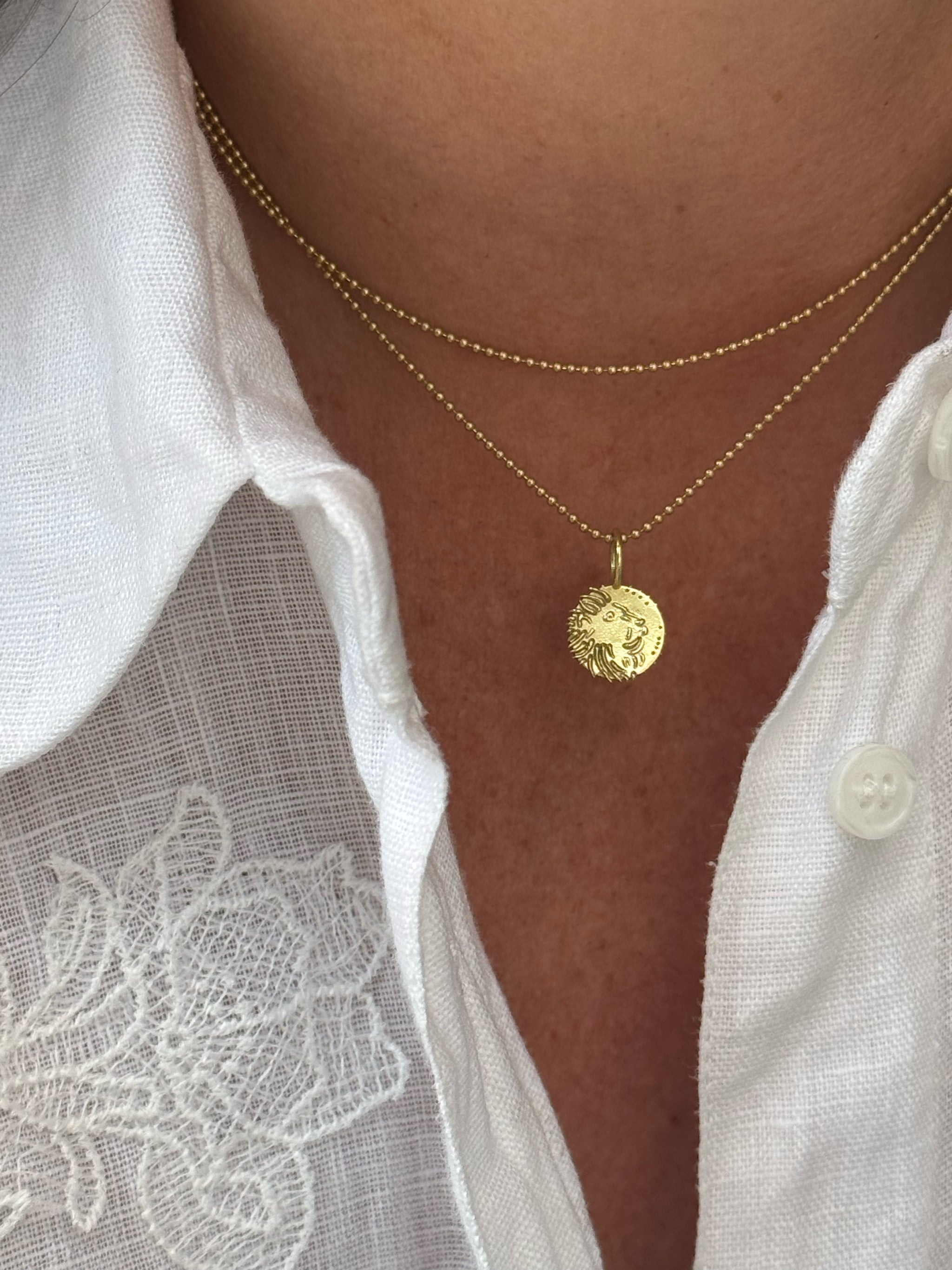 Hand-carved Bébé Lion 18k recycled gold charm on a delicate gold ball chain, double-wrapped around the neck.