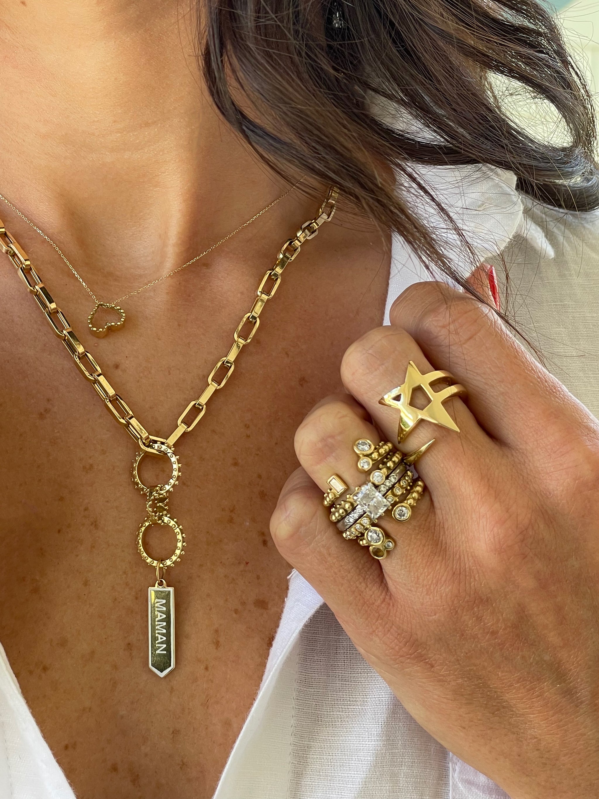 Close-up of 18k recycled gold jewelry including a maman modular necklace, Boheme Stack and etoile rings.