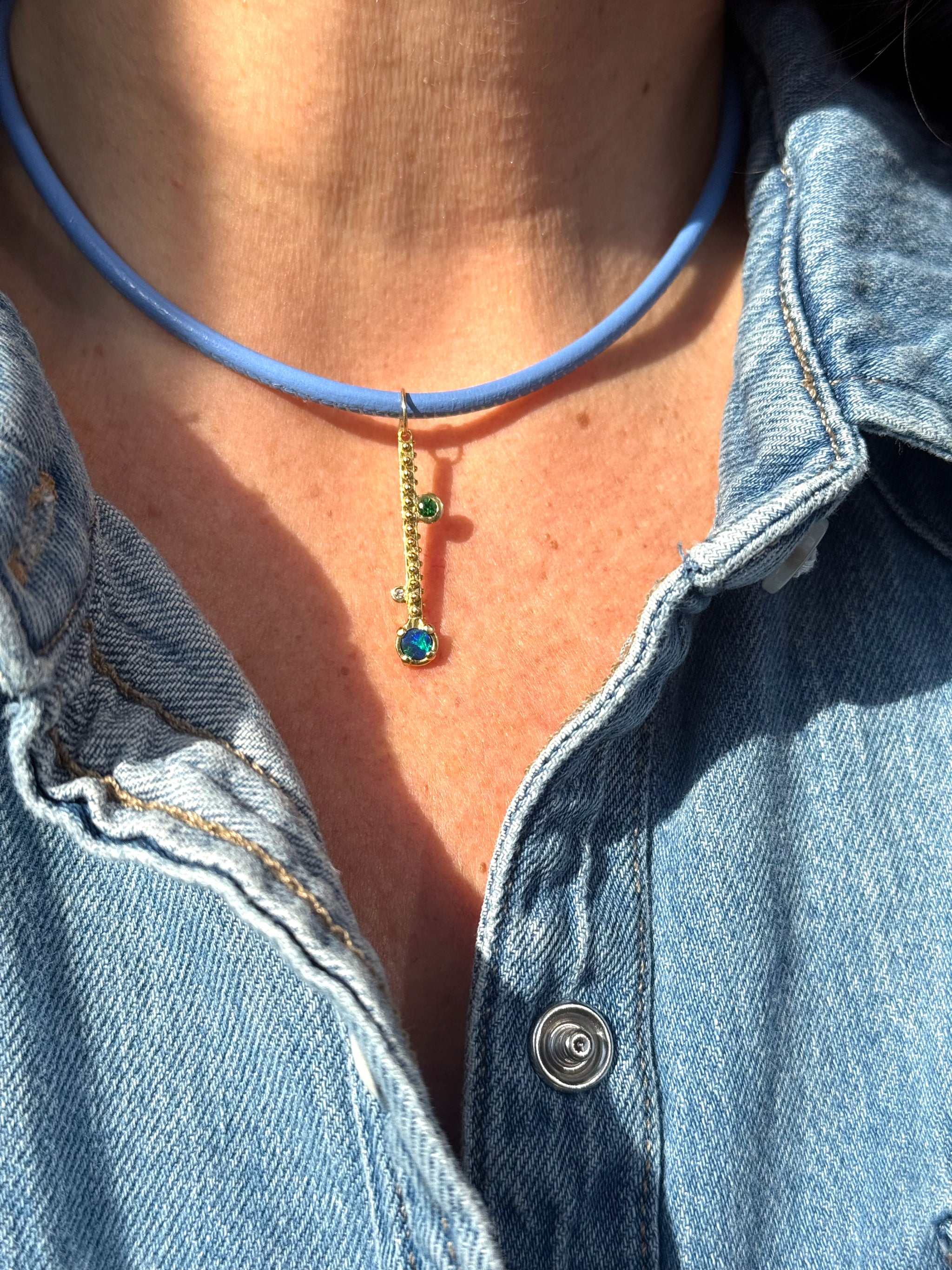 Sacred Link periwinkle blue leather cord worn with Delphine Leymarie opal talisman charm, by model in a denim shirt .