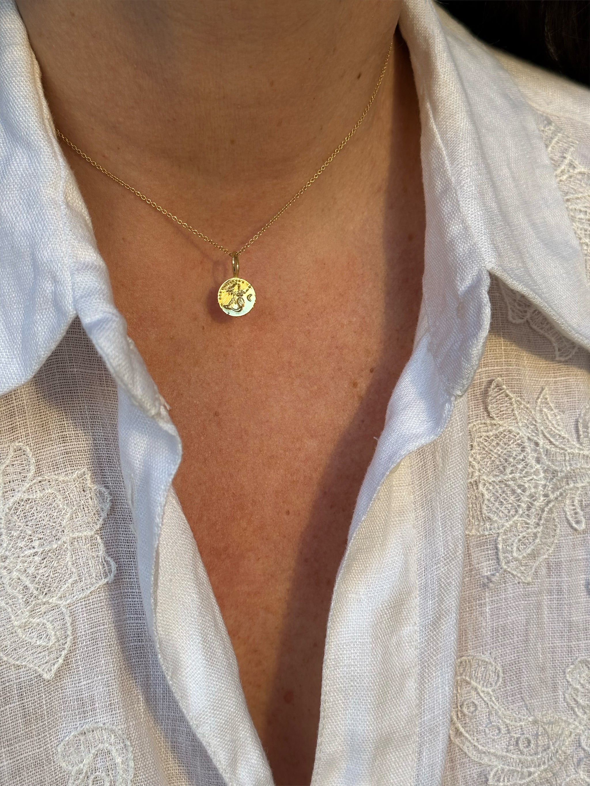 Solid 18k recycled gold tiny mermaid medallion Necklace worn with a white linen shirt with lace details.