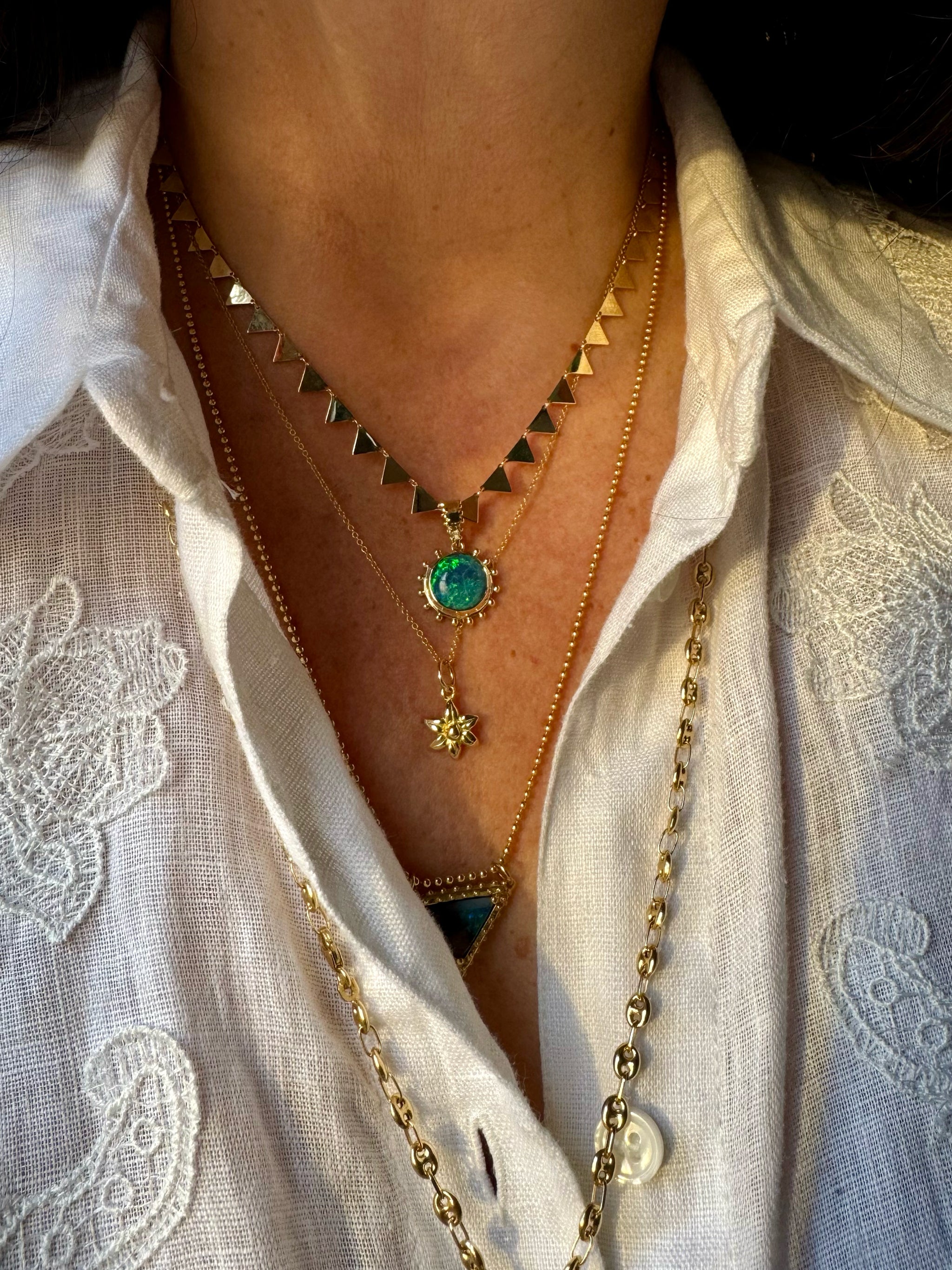 Layered Delphine Leymarie gold necklaces with Boheme Grand Soleil Australian opal charm, Petite Fleur charm, and triangle chain