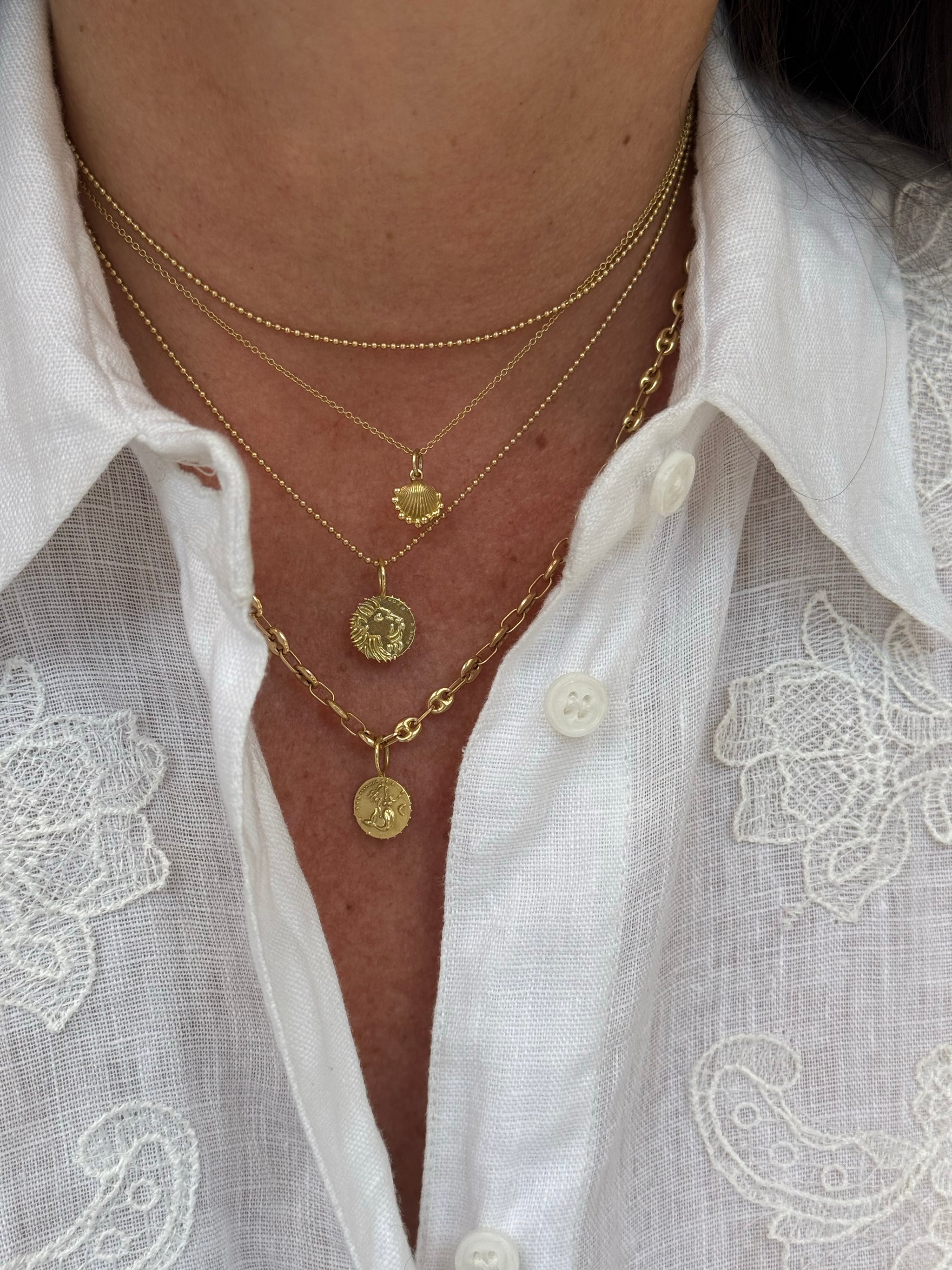 Petite Shell charm layered with Lion and Sirène talismans in solid 18k gold