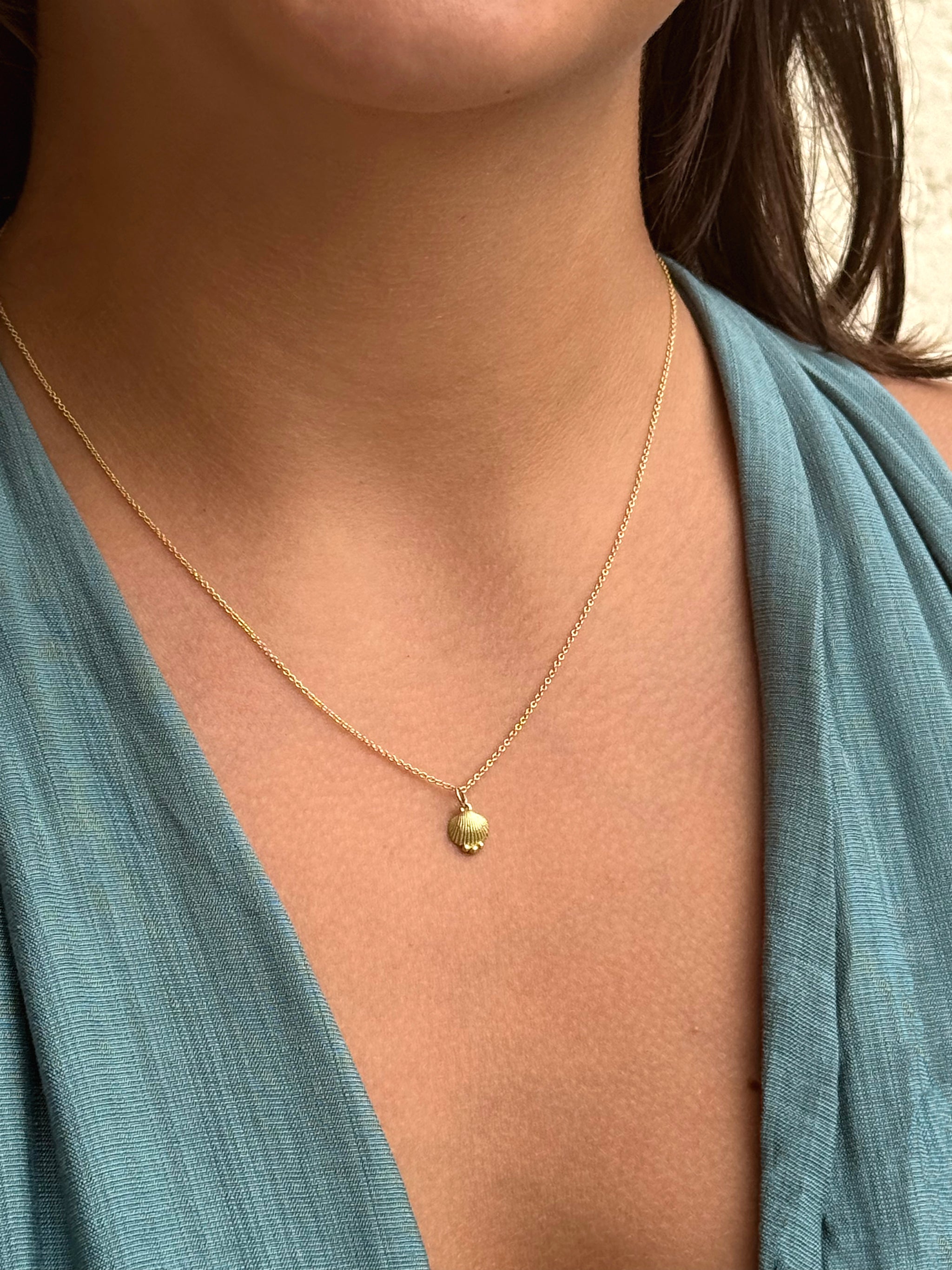 Close-up of a person wearing the Delphine Leymarie adjustable gold chain with the SeaSpell Petite Shell pendant