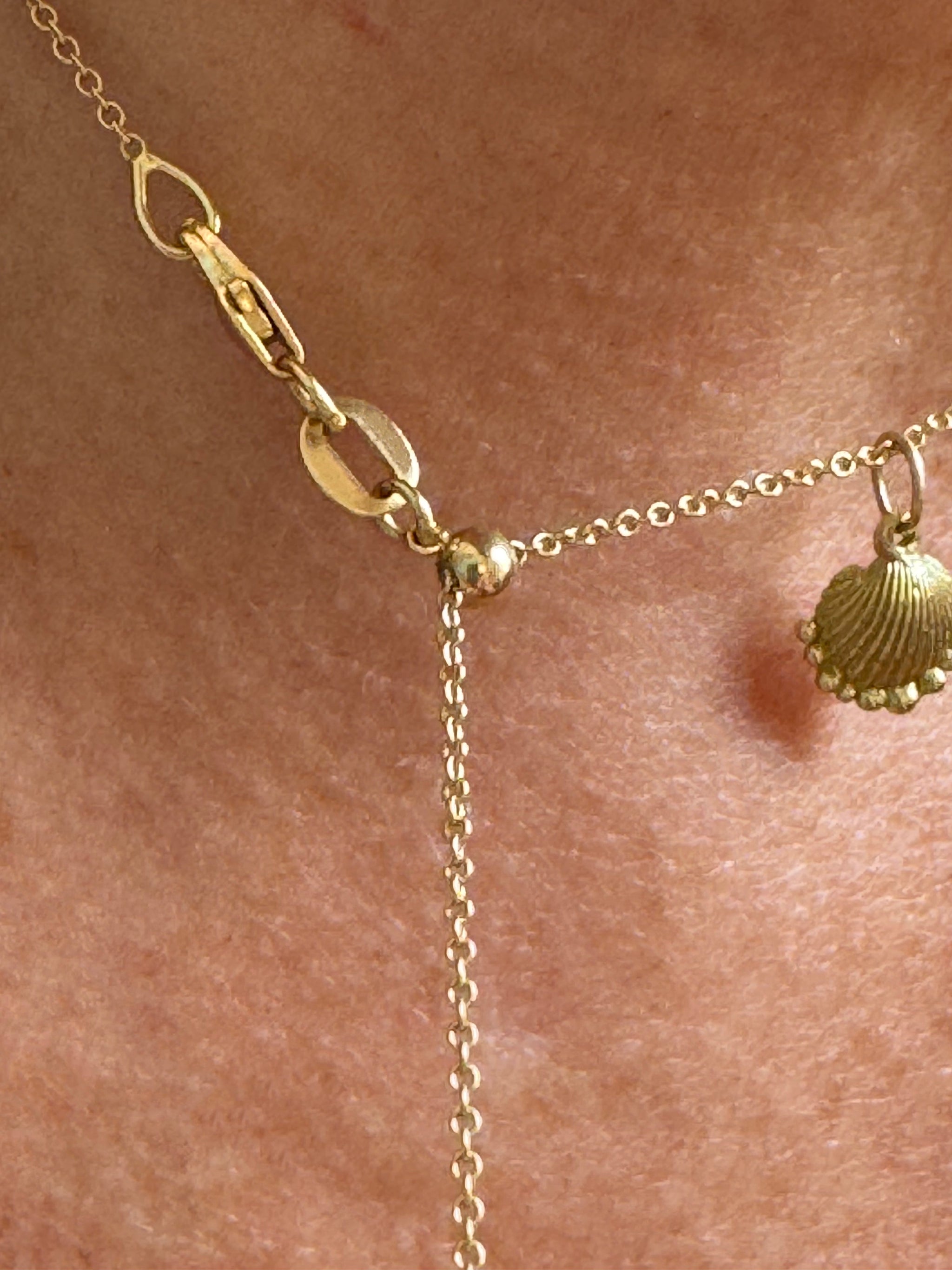 Close-up of 18k adjustable gold cable chain by Delphine Leymarie, worn with Petite Shell charm as a talisman of protection.