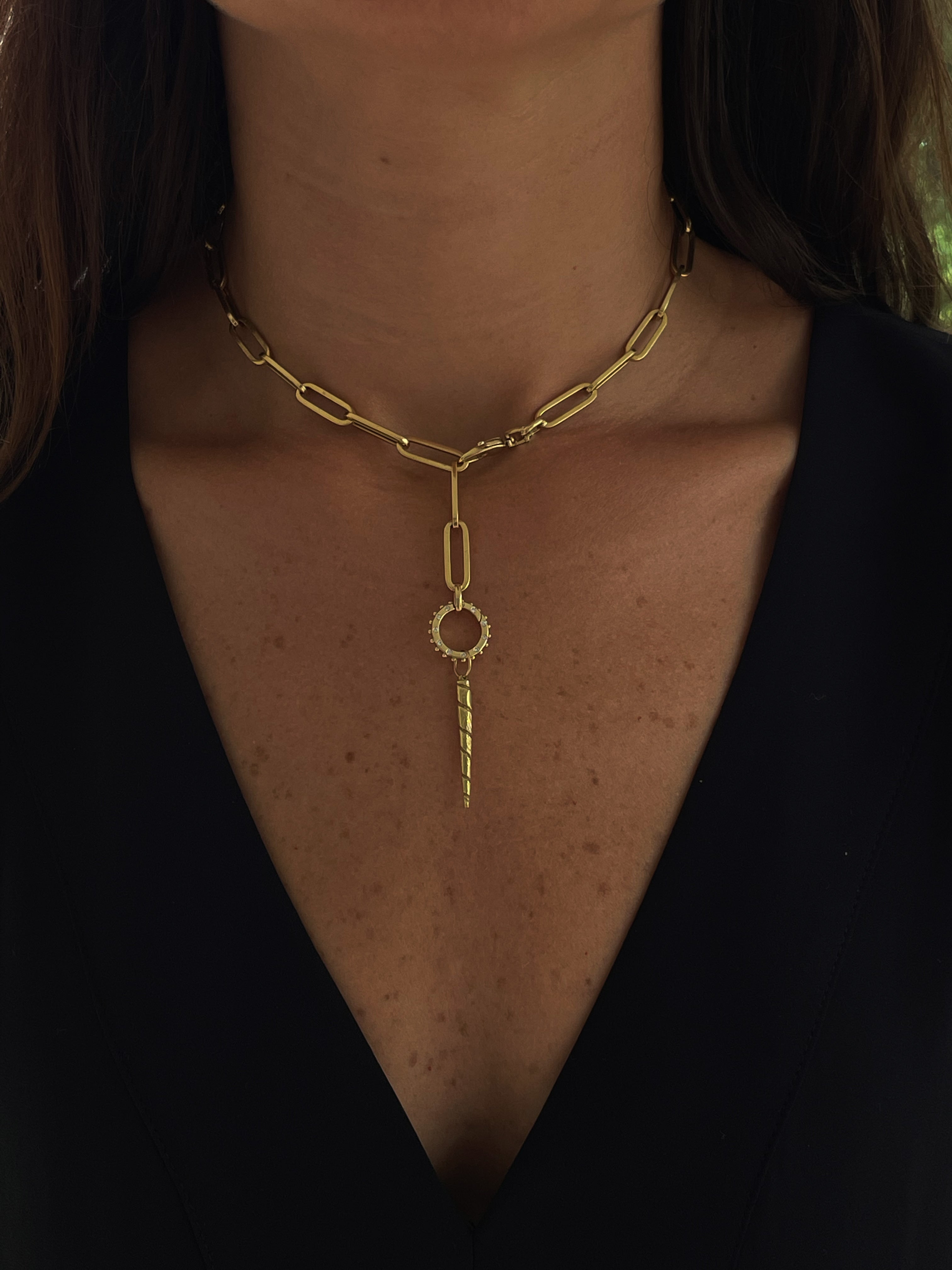 18k recyceld gold Lover necklace with a Unicorn Horn pendant worn as a lariat talisman with a Boheme Clicker by a person against a black background