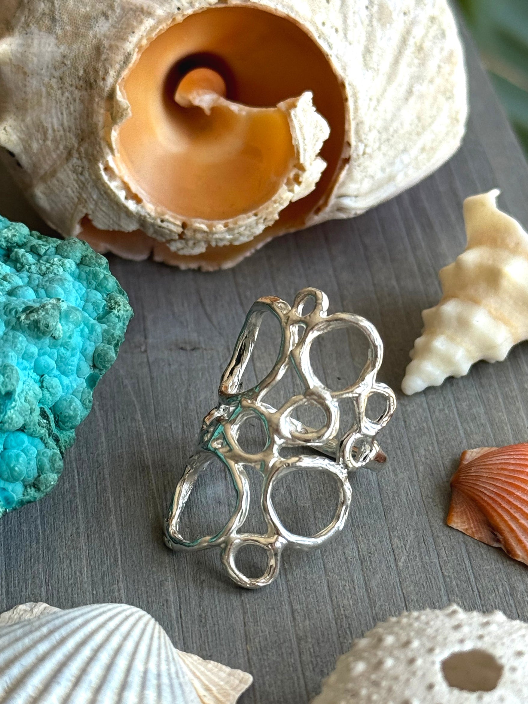 Ecume Ring shown beside ocean Shells, capturing the movement of Sea Foam in sculpted silver.