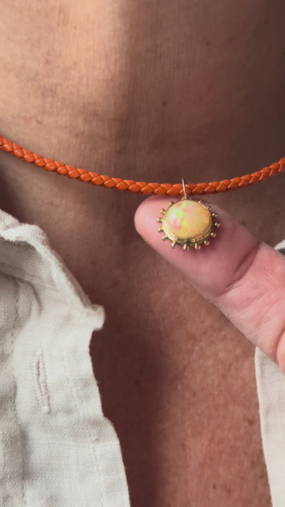 Video of Delphine Leymarie Ethiopian opal Grand Soleil sun charm on Sacred Link orange braided leather cord, worn as a talisman necklace.